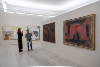 zwei Frauen stehen in einem Ausstellungsraum mit Gemälden