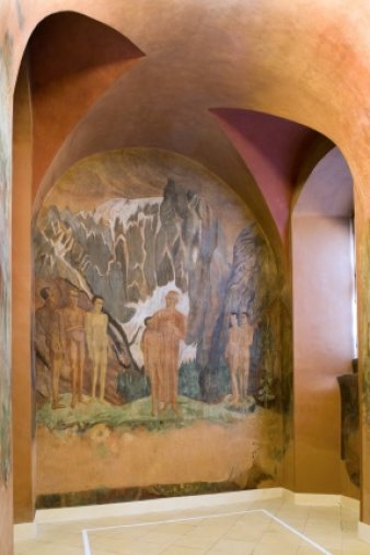 Blick auf eine Seite der Wandmalerei, auf der im Vordergrund nackte Männer und im Hintergrund schroffe Felsen zu sehen sind