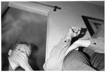 Ein mann hält sich die Hand vor den Mund, eine andere Person hält eine Zigarette in der Hand, schwarz-weiß Foto