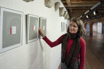 Eine Frau steht vor Bildern, die an einer Wand hängen