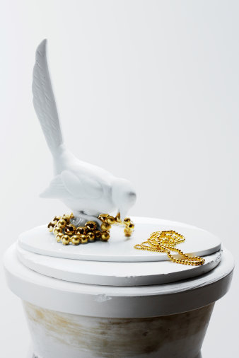 Porzellanfigur eines Vogels, begleitet von goldenen Ketten