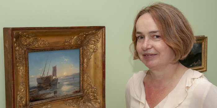 Dr. Claudia Denk in der Sonderausstellung im Angermuseum Erfurt Eine Frau steht neben dem gerahmten Öl-Gemälde "Boote am Strand bei Ebbe" Théodore Gudin