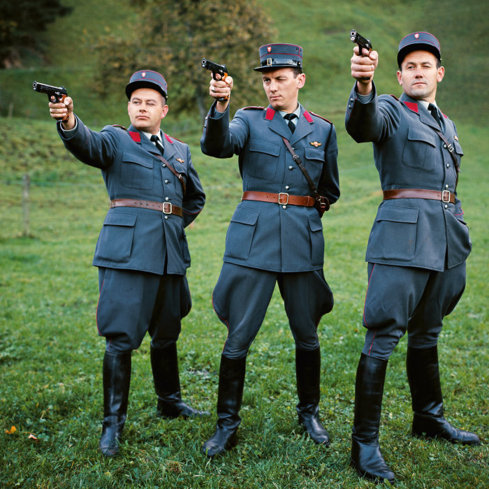 Drei Männer in Uniform zielen mit ihren Pistolen auf ein gemeinsames Ziel.
