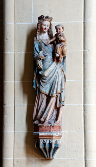 Eine geschnitzte Madonnen-Figur aus Holz an einer Säule.