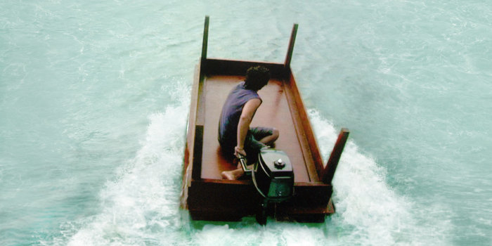 Ein umgedrehter Tisch mit einem eingebauten Motor dient einem jungen Mann als Boot