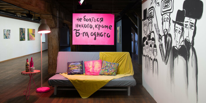 ein Sofa mit Kissen und einer Stehlampe ist umrahmt von verschiedenen Kunstwerken