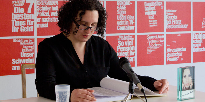 eine Frau liest vor ainem Mikrofon aus einem Buch