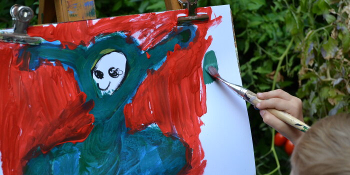 ein Kind malt mit Pinsel und Farbe auf Papier