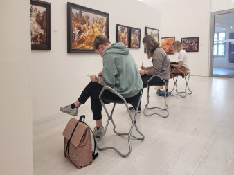 Mehrere Personen sitzen mit Stift und Block vor einem Bild