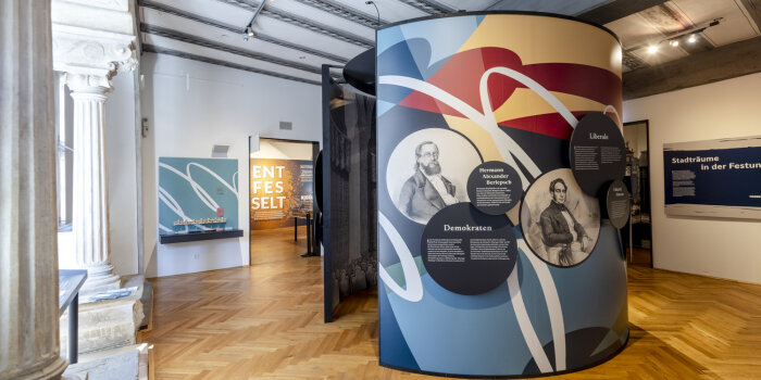 eine kreisförmige Ausstellungsinstallation mit Grafiken, Fotos und Texten