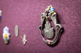 ein Amulett, das Mittelstück hat die Form einer Hand und trägt eine Prägung der Stadt Jerusalem