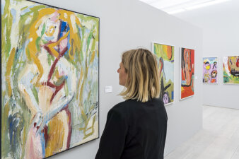Eine Frau schaut sich ein buntes Gemälde an