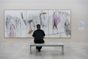 eine Person sitzt vor einem großen Gemälde
