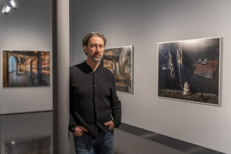 ein Mann steht in einem Ausstellungsraum mit Fotografien