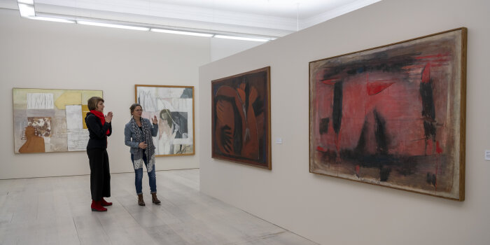 zwei Frauen stehen in einem Ausstellungsraum mit Gemälden