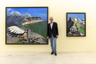 ein Mann steht neben zwei großen bunten Gemälden