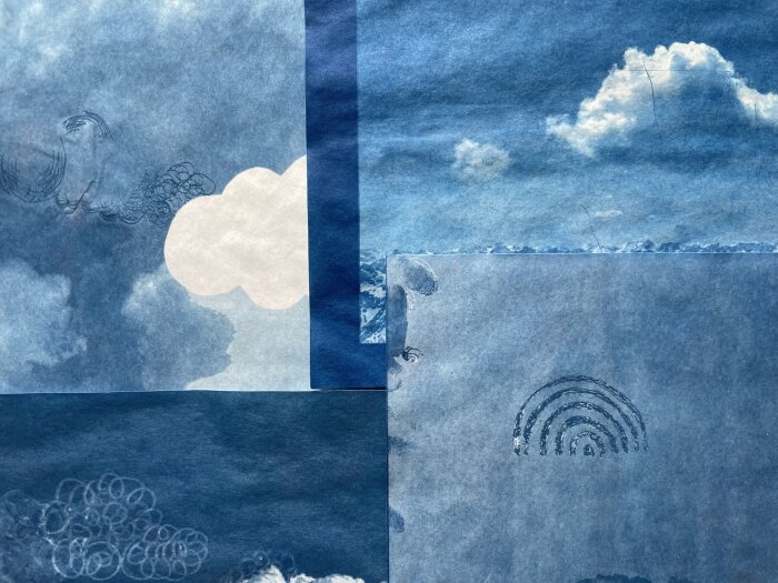Mehrere Cyanotypie Papierstücke mit Wolken- und Regenbogenmustern liegen übereinander