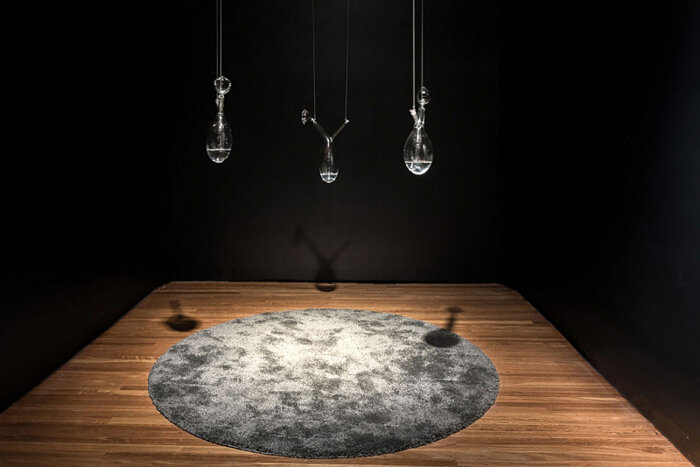 Installation von drei hängenden Glasgefäßen mit einem grauen Teppich auf einem Holzfußboden.