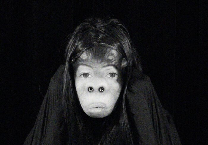 Schwarz Weiß Bild einer Person mit Affenmaske