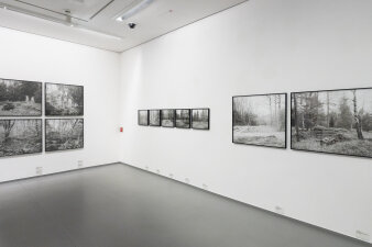 Ein heller Raum mit schwarz weißen Fotografien an der Wand.