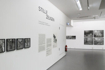 Ein heller Raum mit Schrift und schwarz weißen Fotografien an der Wand.