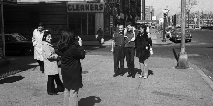 Schwarz Weiß Fotografie einer Gruppe von Personen die von einer Frau fotografiert werden.