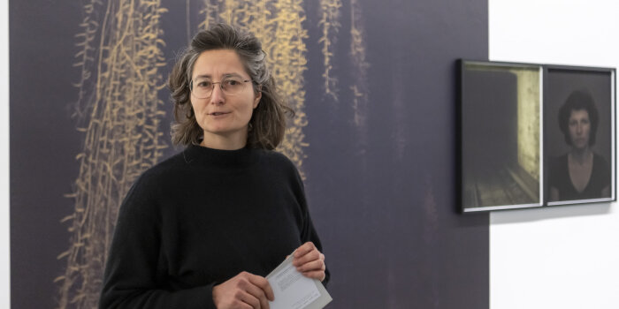 Foto: Ausstellung Next Generation #2 in der Kunsthalle | Nora Klein © Stadtverwaltung Erfurt/Dirk Urban eine Frau in schwarzem Pullover vor einer Wand mit großformatigen Fotografien