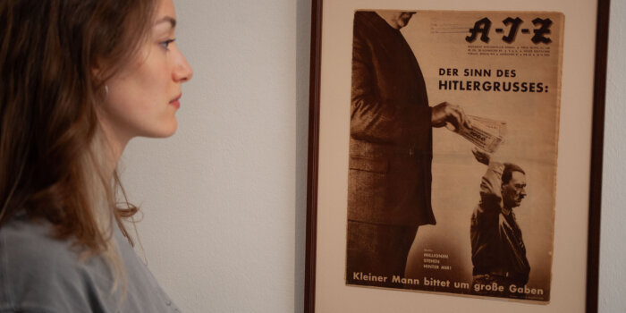 Eine junge Frau betrachtet ein braunes gerahmtes Plakat mit zwei Figuren