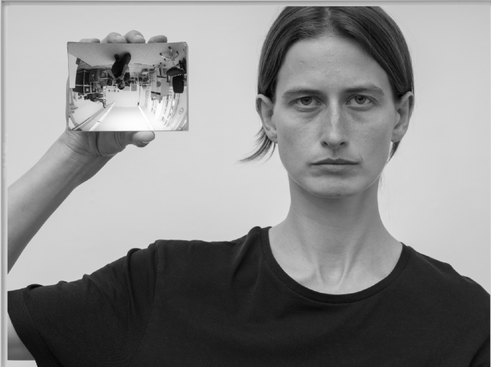 Schwarz Weiß Foto einer Person die einen Spiegel in der  gehobenen Hand hält