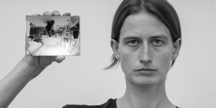 Schwarz Weiß Foto einer Person die einen Spiegel in der  gehobenen Hand hält