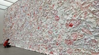 Kunstinstallation an einer Wand, die wie zerknülltes Papier wirkt