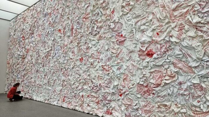 Kunstinstallation an einer Wand, die wie zerknülltes Papier wirkt