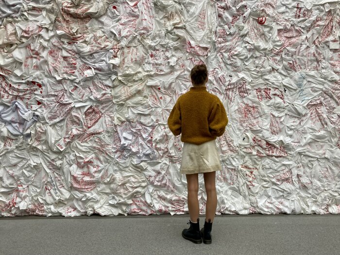 Eine mit weißen Stoffen behangene Wand, davor eine Person stehend