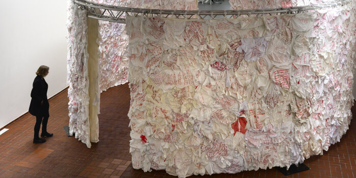 Eine raumgreifende Installation mit weiß-rotem Stoff, daneben eine Person stehend