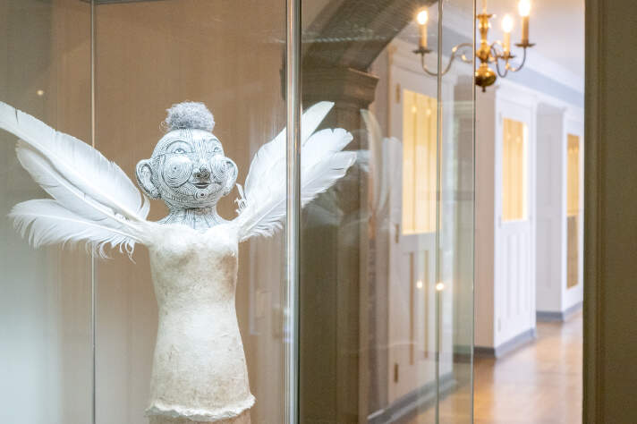 Eine helle Statur mit Flügeln in einer Vitrine