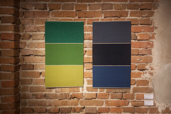 Zwei Kunstwerke mit Streifen in verschiedenen Grün- und Blautönen vor Backsteinwand