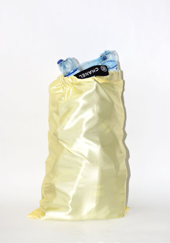Blick auf einen gelben Sack mit blauen leeren Flaschen darin und einem schwarzen Label mit Aufschrift „Chanel“