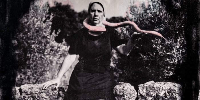 Schwarz Weiß Portrait einer Frau mit Kopftuch, die eine rosa Schlange um den Hals trägt