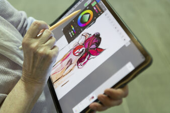 eine Hand arbeitet an einem Grafik-Tablett in einer Mal-App