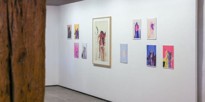 Blick in einen hellen Raum mit bunten Kunstwerken an der Wand