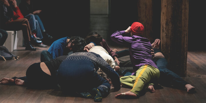 mehrere Menschen bewegen sich im Rahmen einer Tanzperformance am Boden